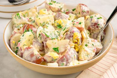 A bowl of potato salad with herbs and dressing