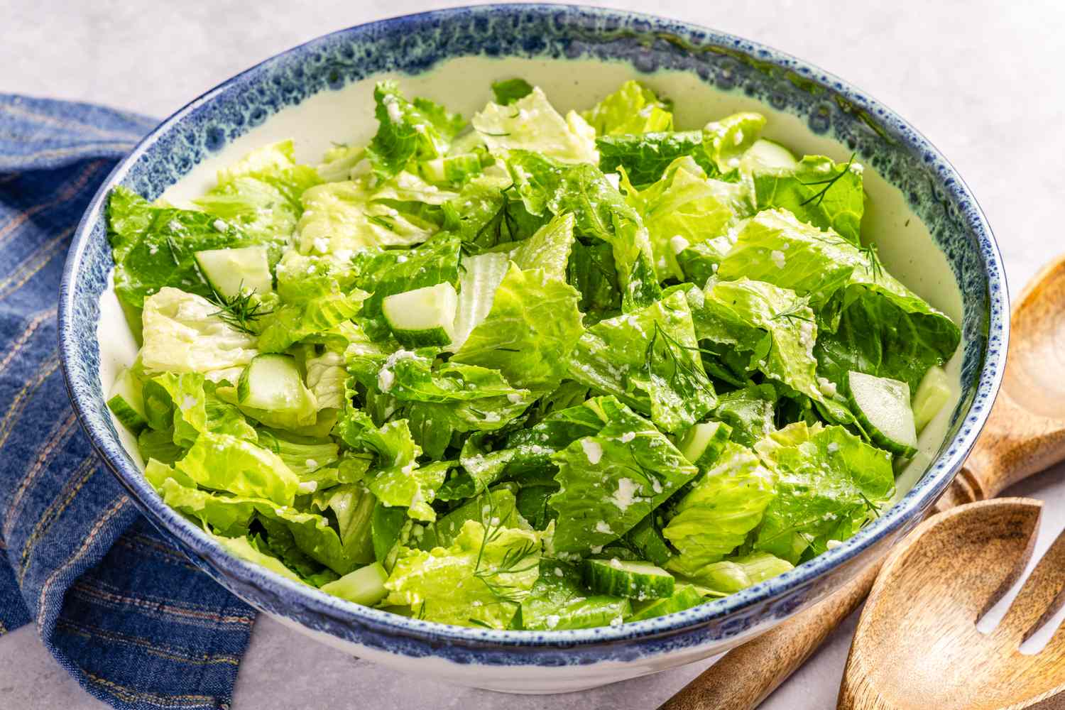 Maroulosalata (greek salad) in a bowl next to serving spoons and a table napkin