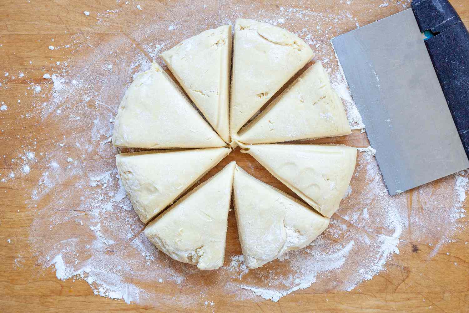 A dough scraper cutting dough into triangles to make the fluffiest brioche buns.