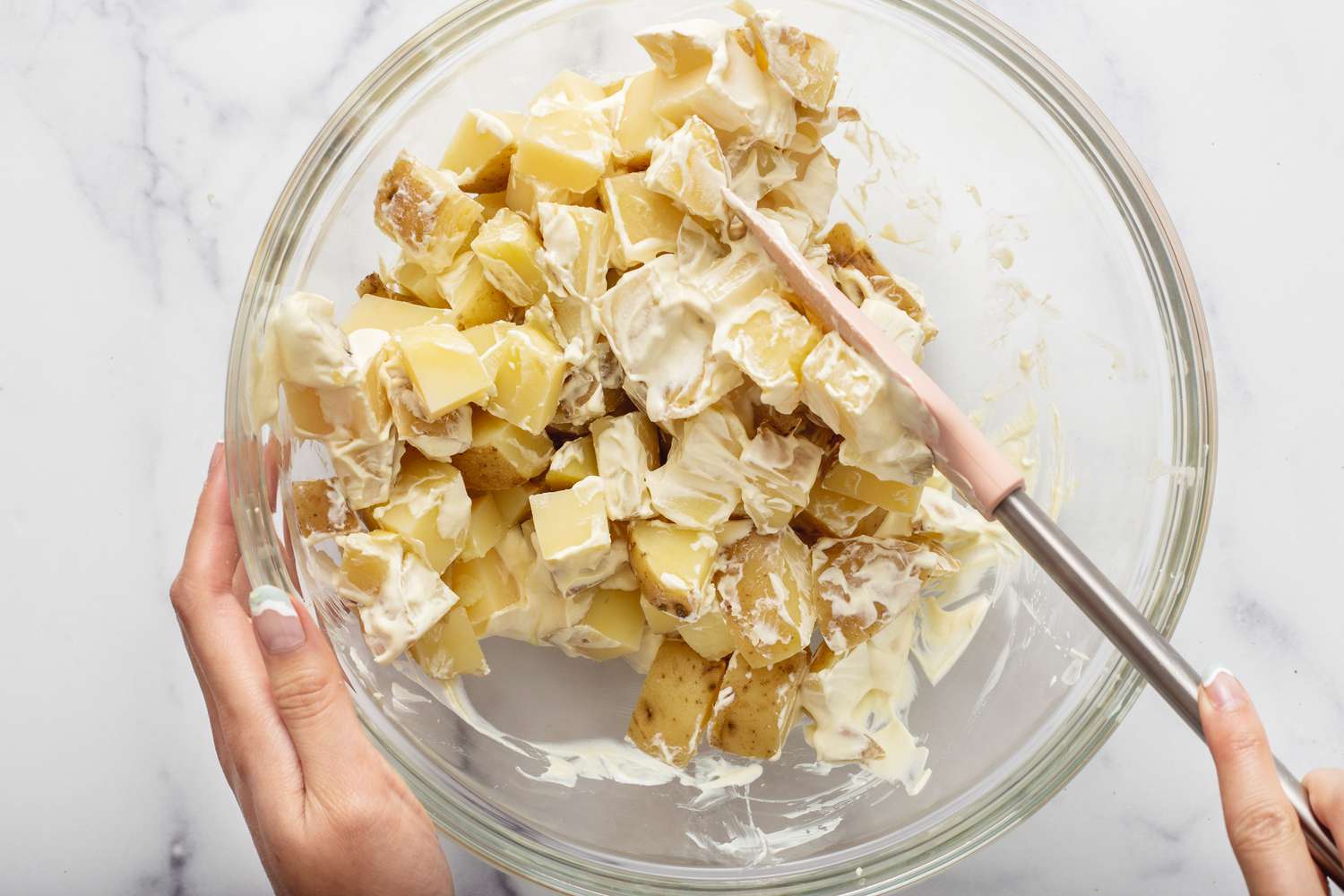 Combining potatoes and dressing for a potato salad recipe.