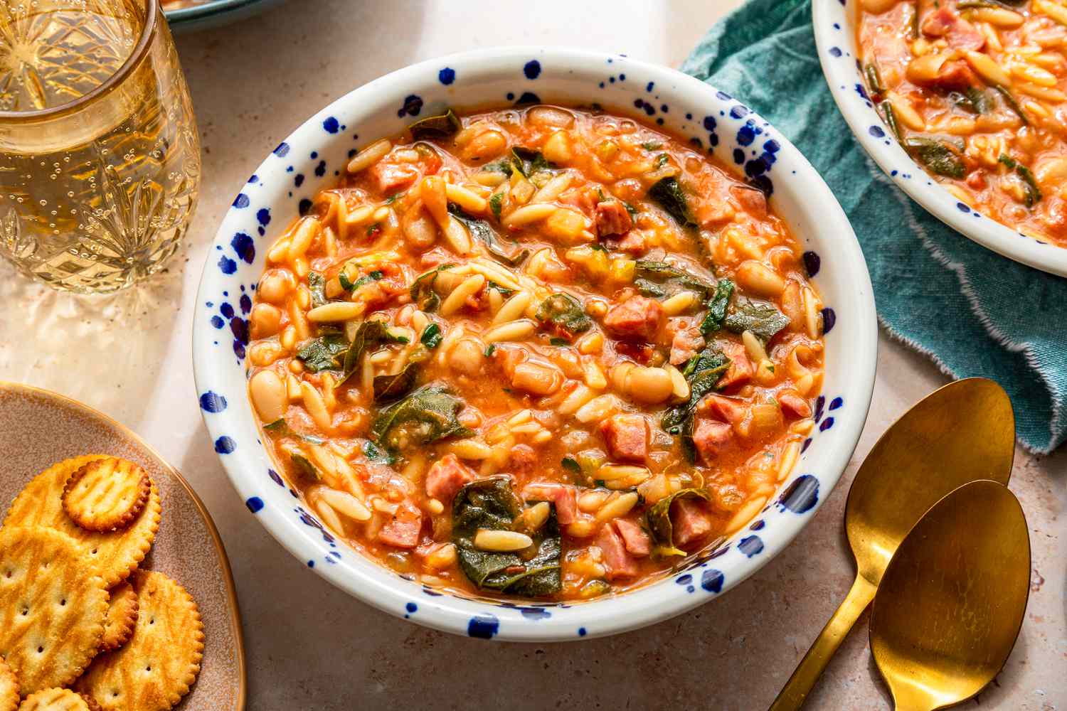 Bowls of swamp soup at a table setting with a glass of water, a bowl of crackers, and a utensils