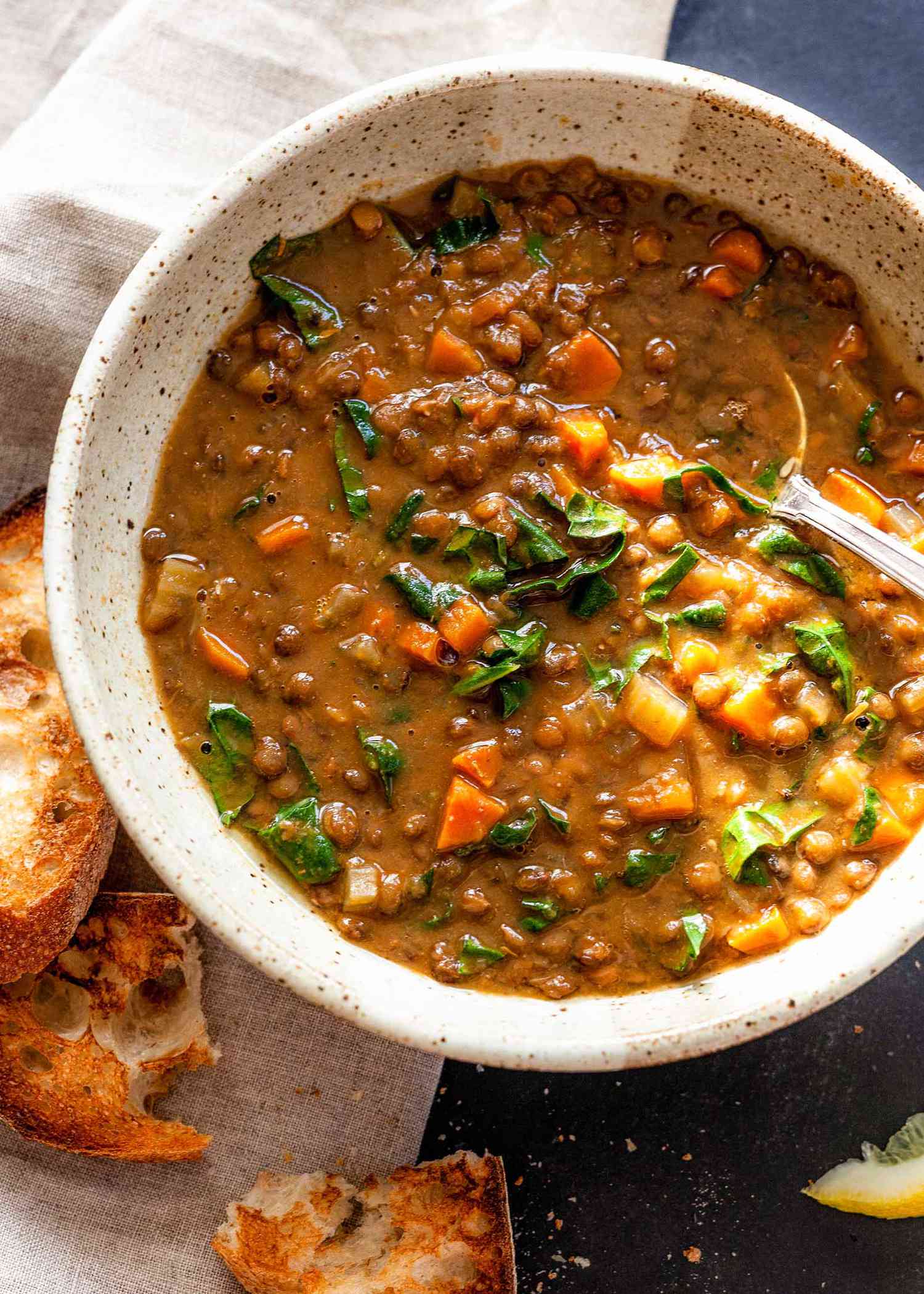 Homemade lentil soup with kale, carrots and tomato paste in a bowl with a spoon.