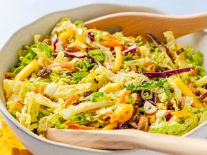 coronation coleslaw with salad serving spoons in a bowl (close-up)