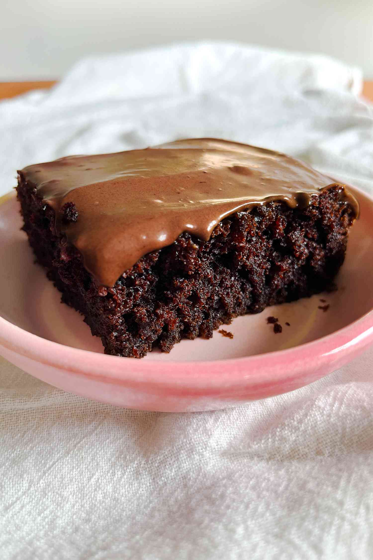 A slice of sour cream chocolate cake on a small pink plate