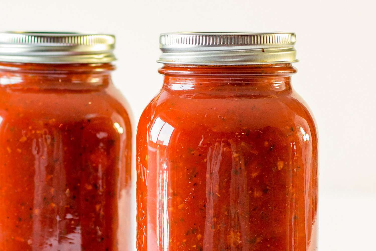 Two jars filled with pasta sauce topped with sealed lids