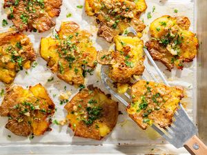 Roasted smashed potatoes with garlic and garnish on a tray
