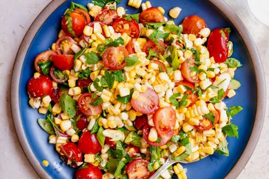 A plate of corn and tomato salad with herbs