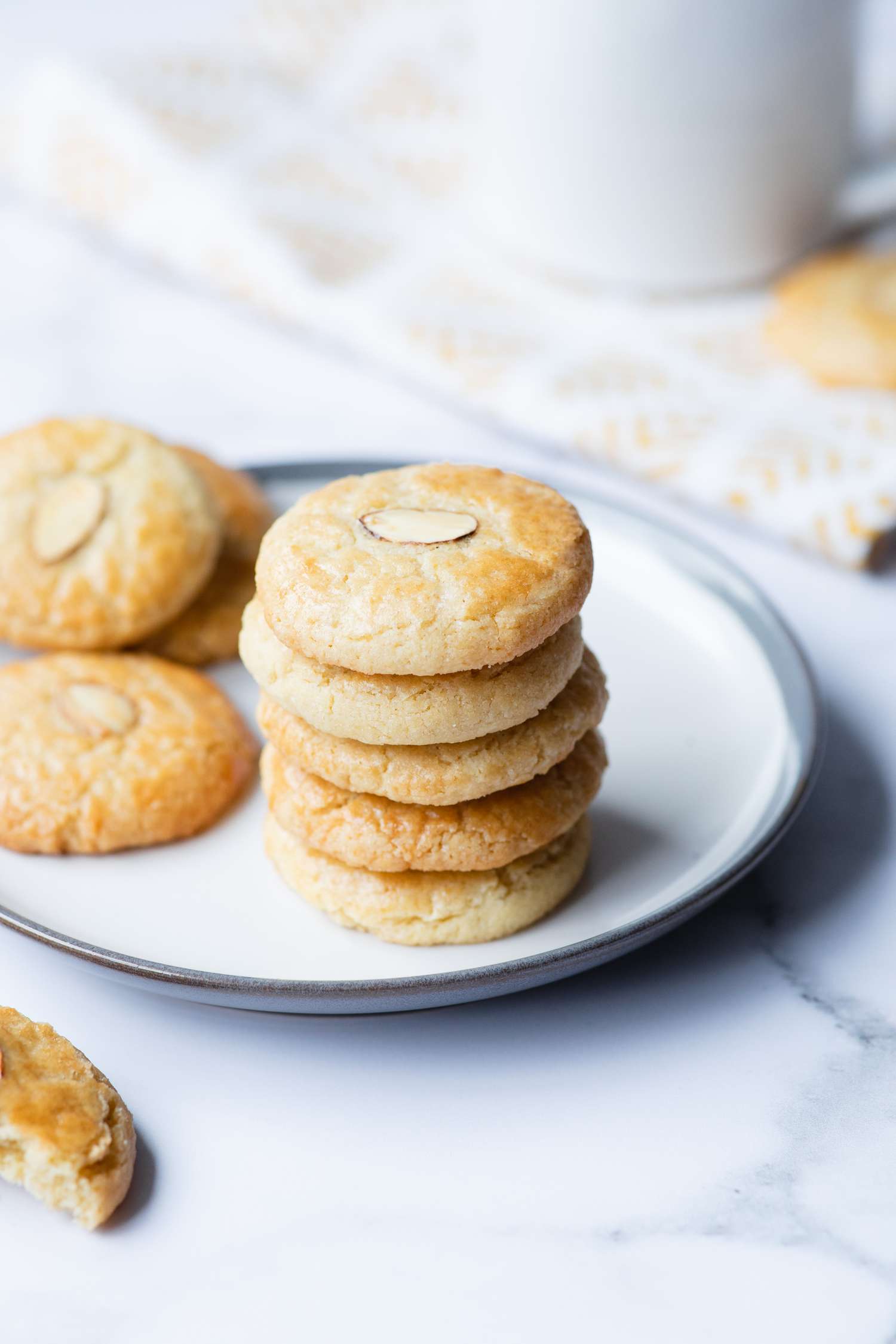 Almond cookies stacked and scattered on a plate.