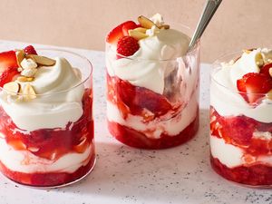 Three glasses of strawberry Eton mess topped with whipped cream and almonds