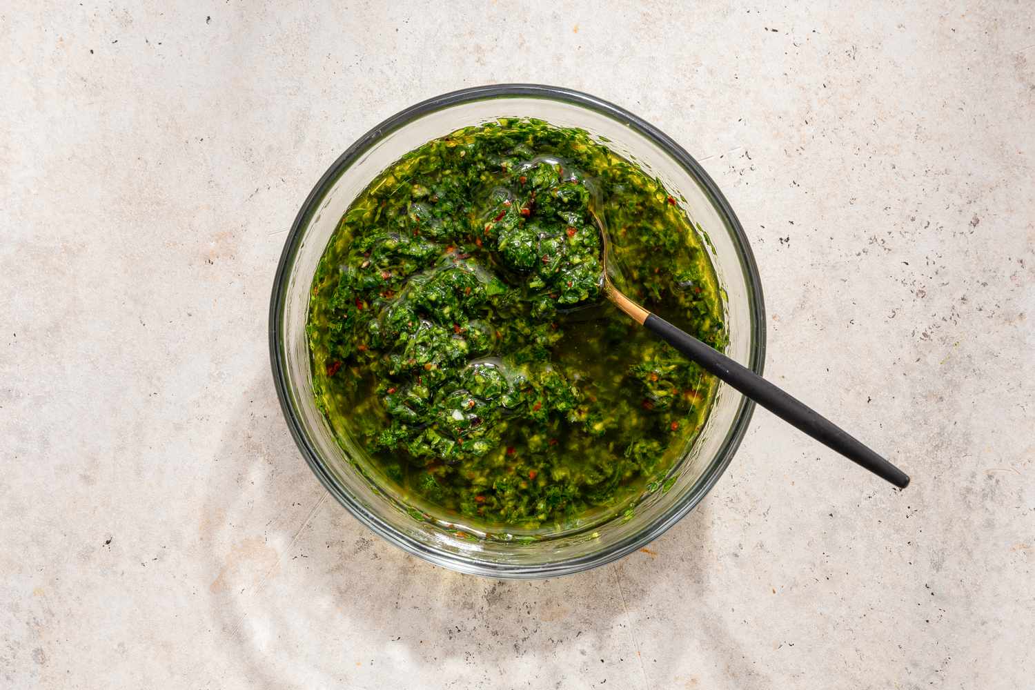 A bowl of chimichurri sauce with a spoon in it