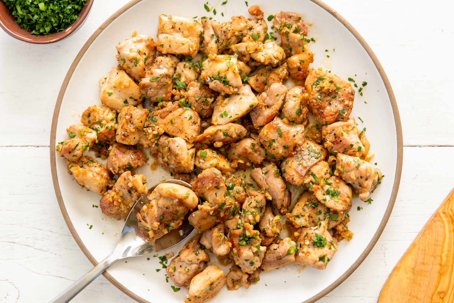 Plate of cooked chicken bites with a garnish, served with a spoon
