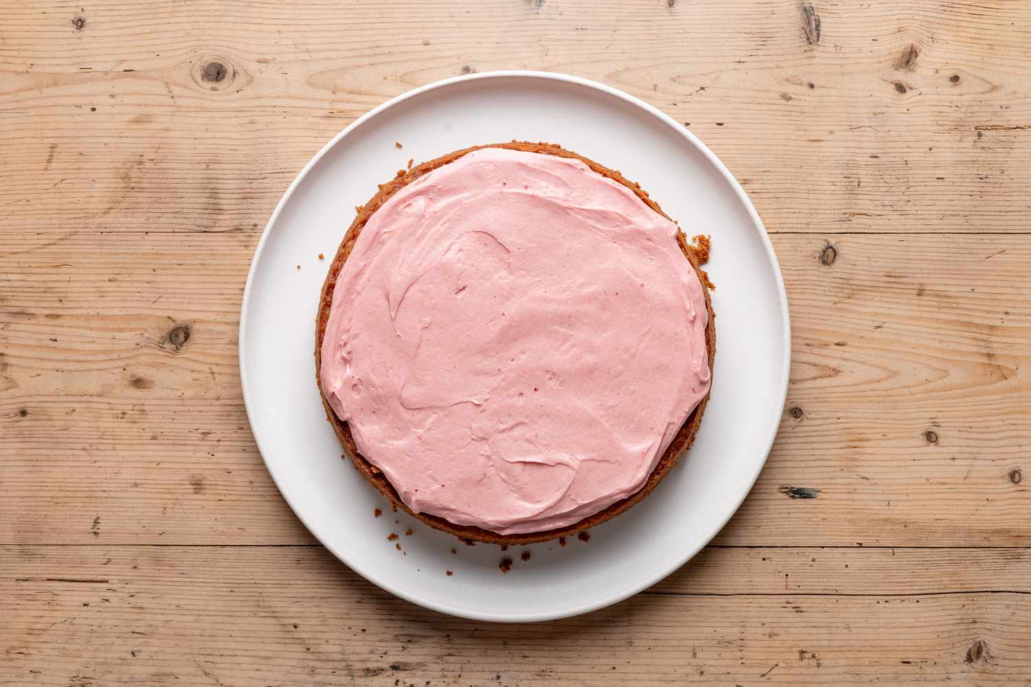 strawberry cake layer on a plate with some icing added spread on top for strawberry cake recipe