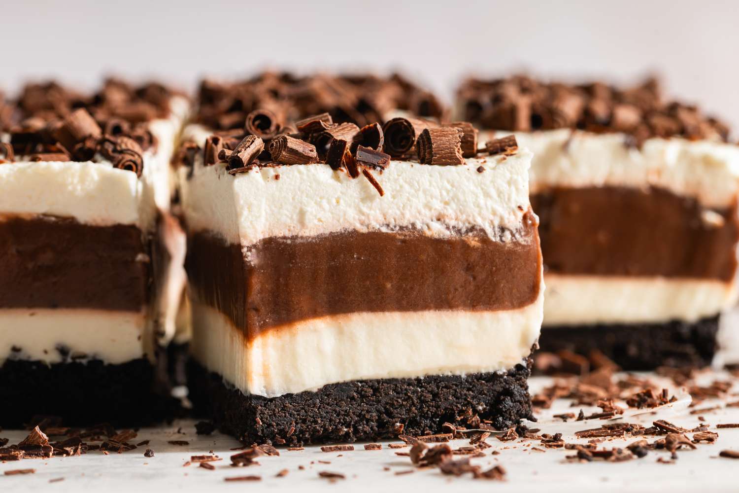 Layered dessert with chocolate whipped cream and cookie crust topped with chocolate shavings