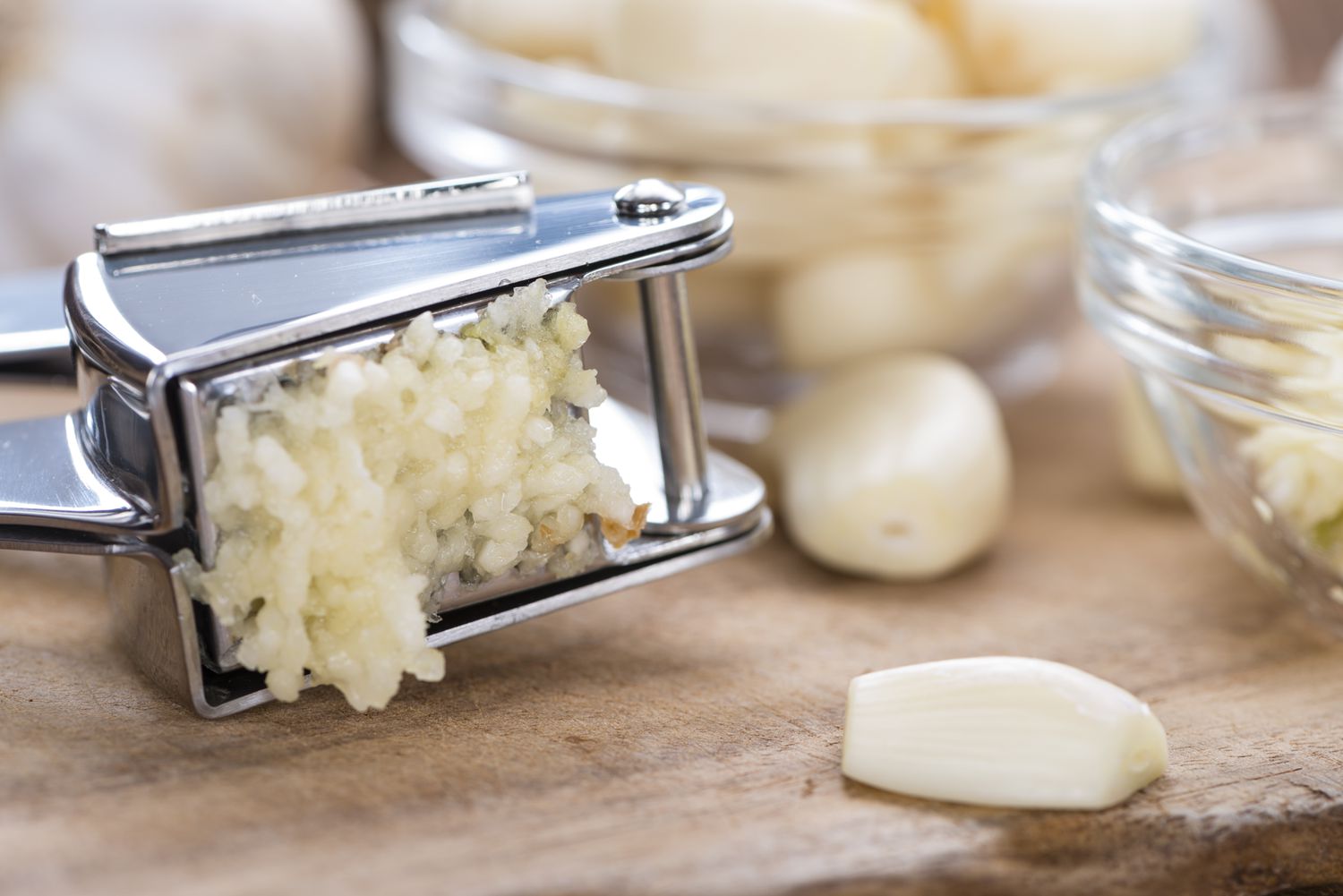 A garlic press with garlic being squeezed out