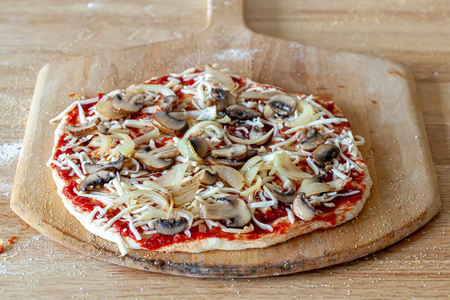 Pizza ingredients spread on pizza dough.