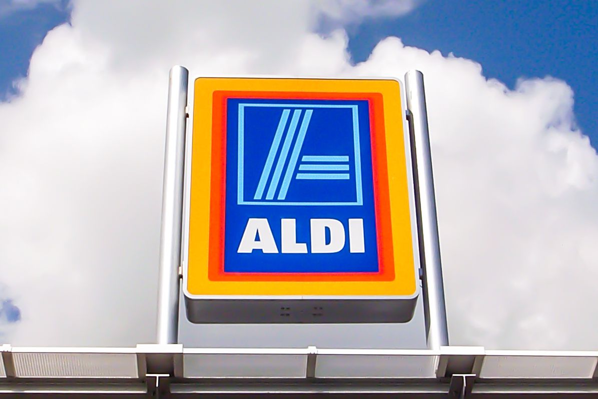 An Aldi sign with clouds and a blue sky in the background