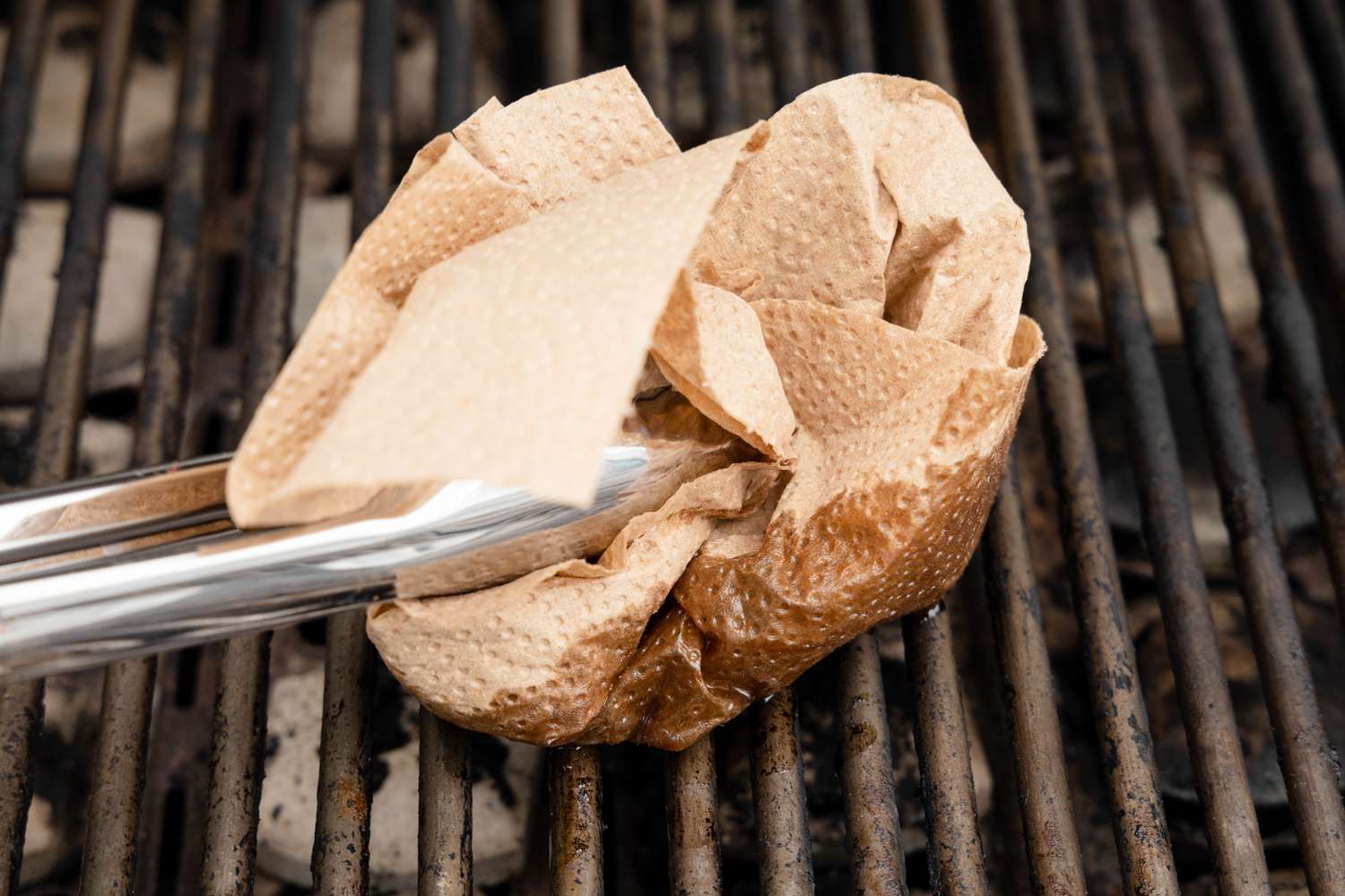 Oil Doused Paper Towel Held Using a Pair of Tongs Used to Oil the Grill Grates