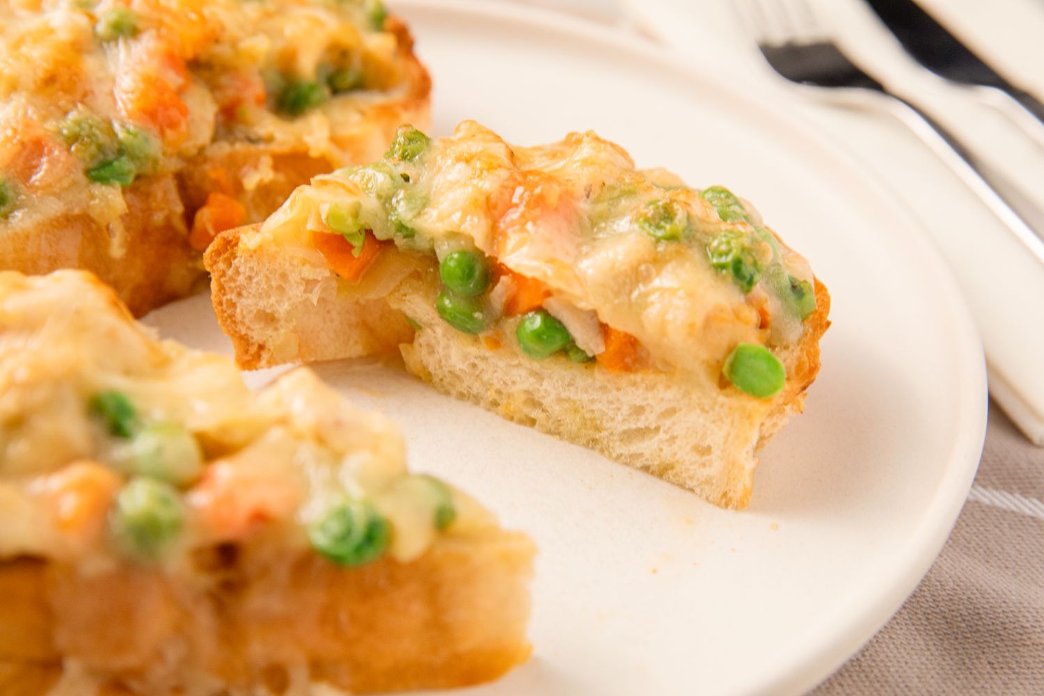 A plate with slices of toast topped with a chicken pot pie filling of vegetables and sauce