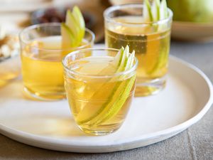 Three glasses of spiced pear bourbon punch on a tray.