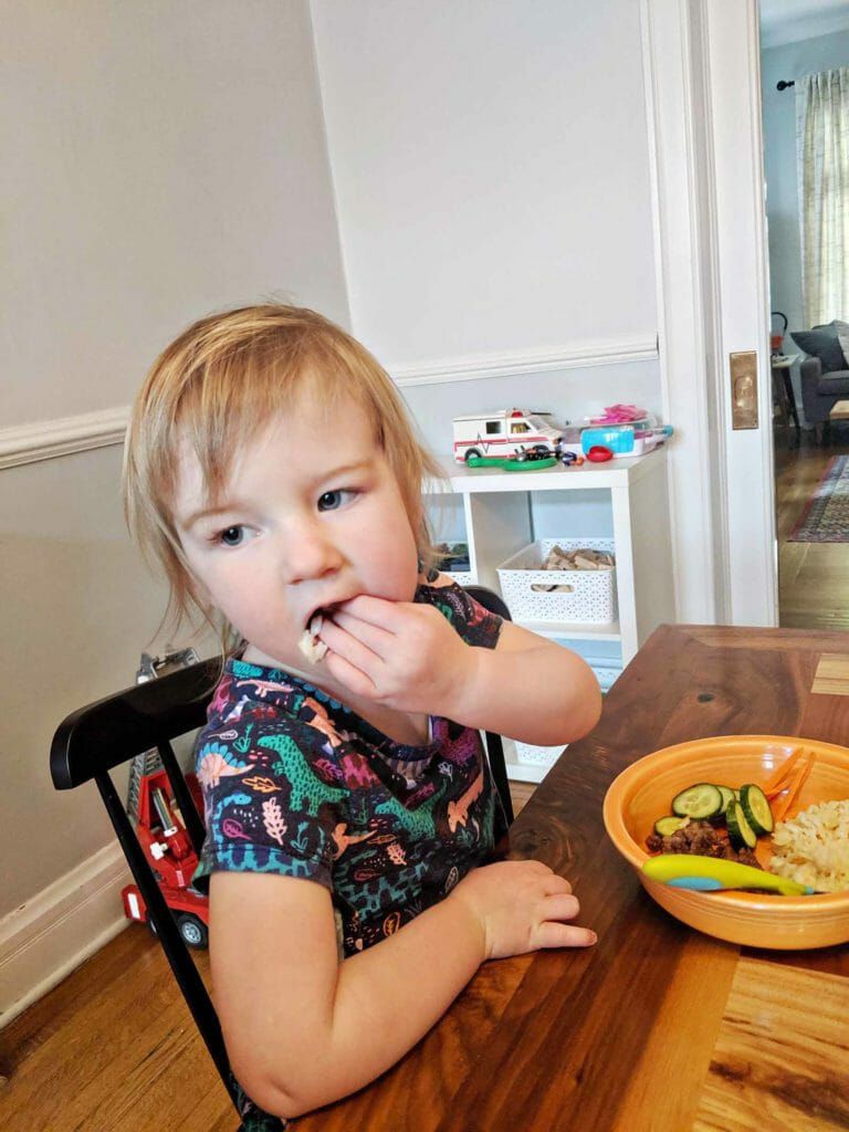 Ginger Pork Rice Bowls - kid with fingers in mouth eating dinner