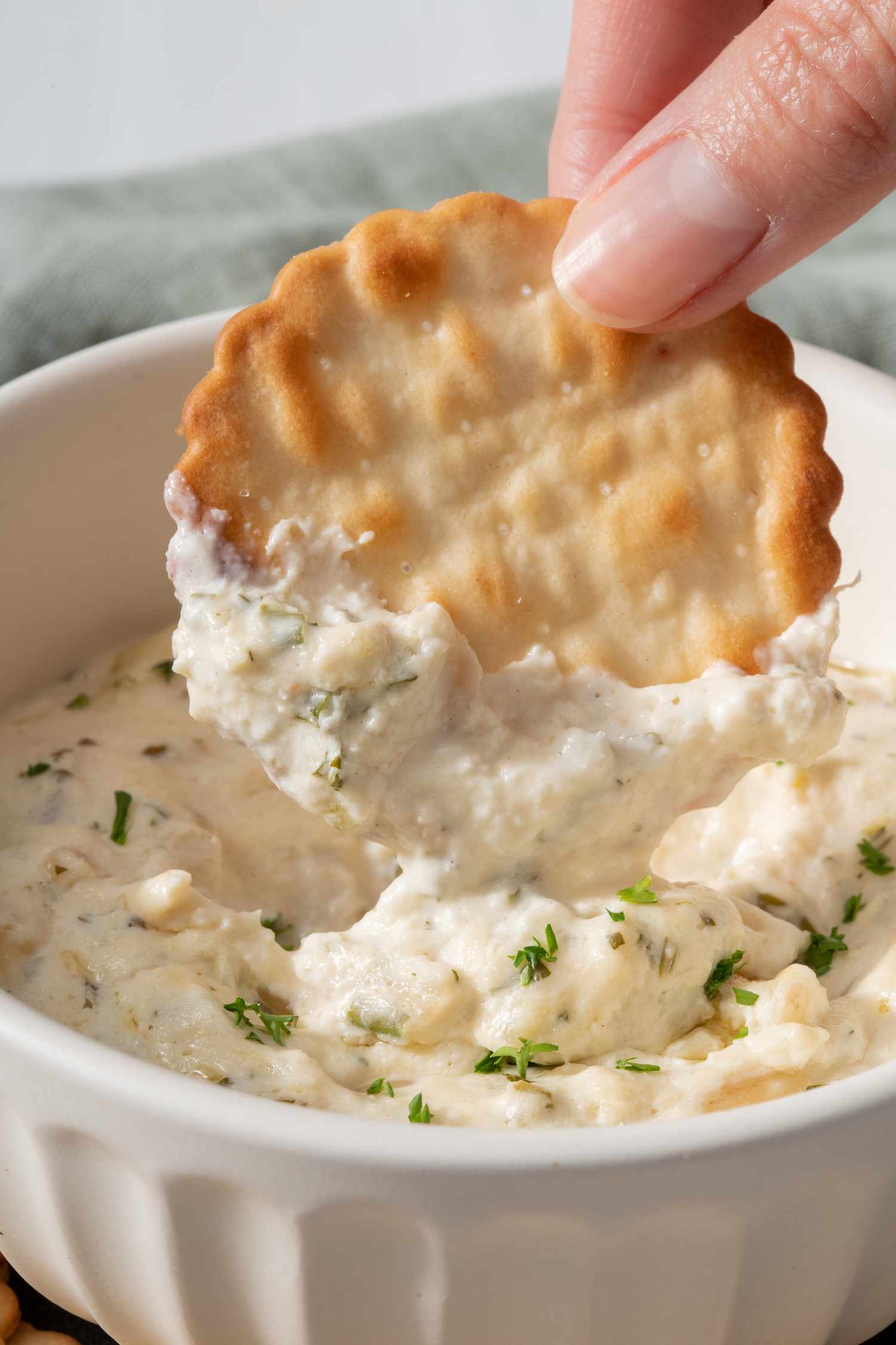 Dipping a cracker in a bowl of crab dip with cream cheese