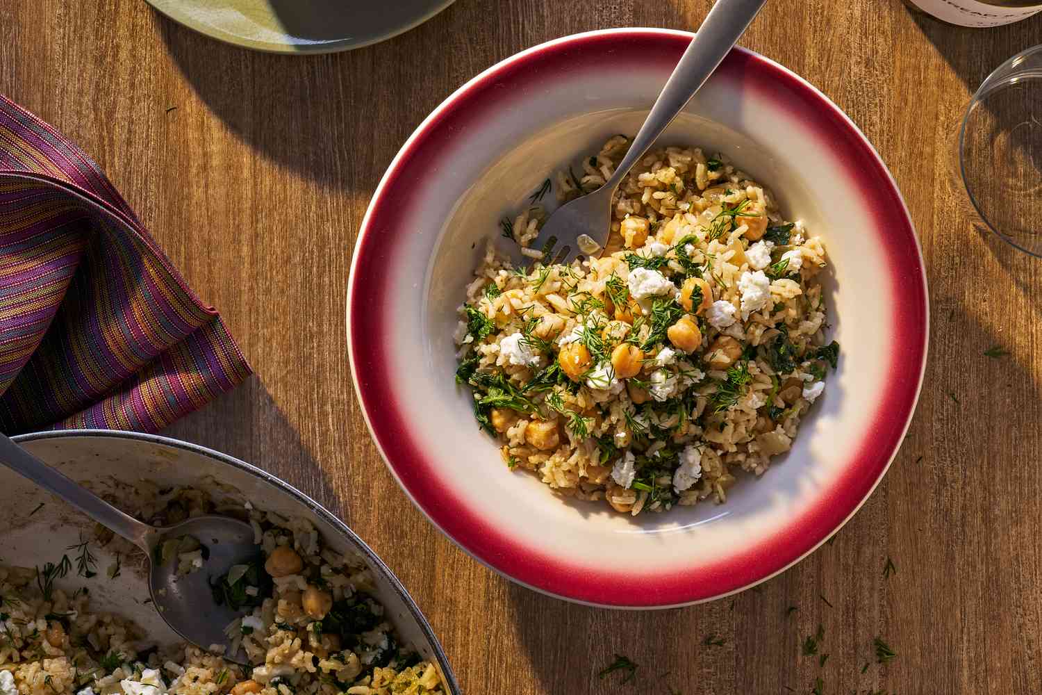 Bowl of chickpea and spinach rice with skillet peeking in