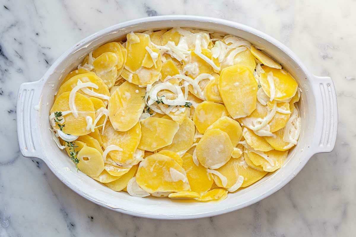 Homemade Aug Gratin Potatoes with thinly sliced potatoes layered in an oval baking dish.
