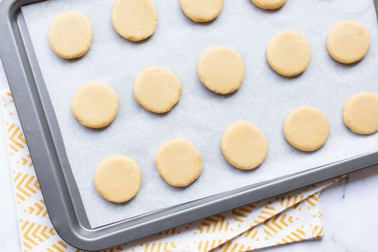 Flattened dough balls on a baking sheet for a Chinese almond cookie recipe.