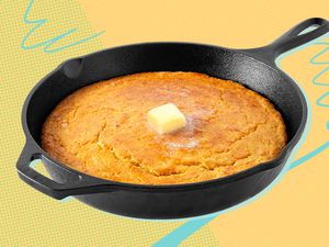 Cast iron skillet of cornbread with a pat of butter in the center on a yellow background