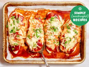 Baked chicken breasts topped with melted cheese and green onions on a baking sheet with a spoon Simply Weeknight Recipes logo in corner
