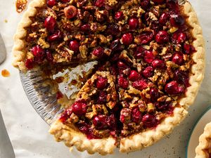 Cranberry pecan pie with a slice removed displayed in a pie dish