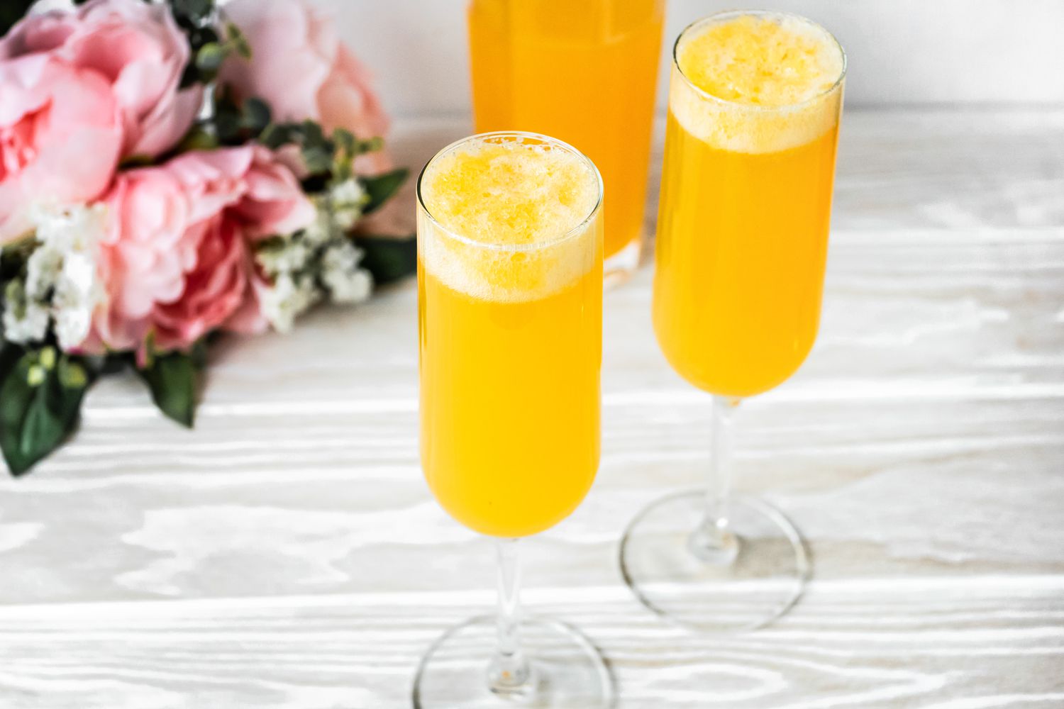 Flutes of Peach Belini Cocktail with Flowers in the Background