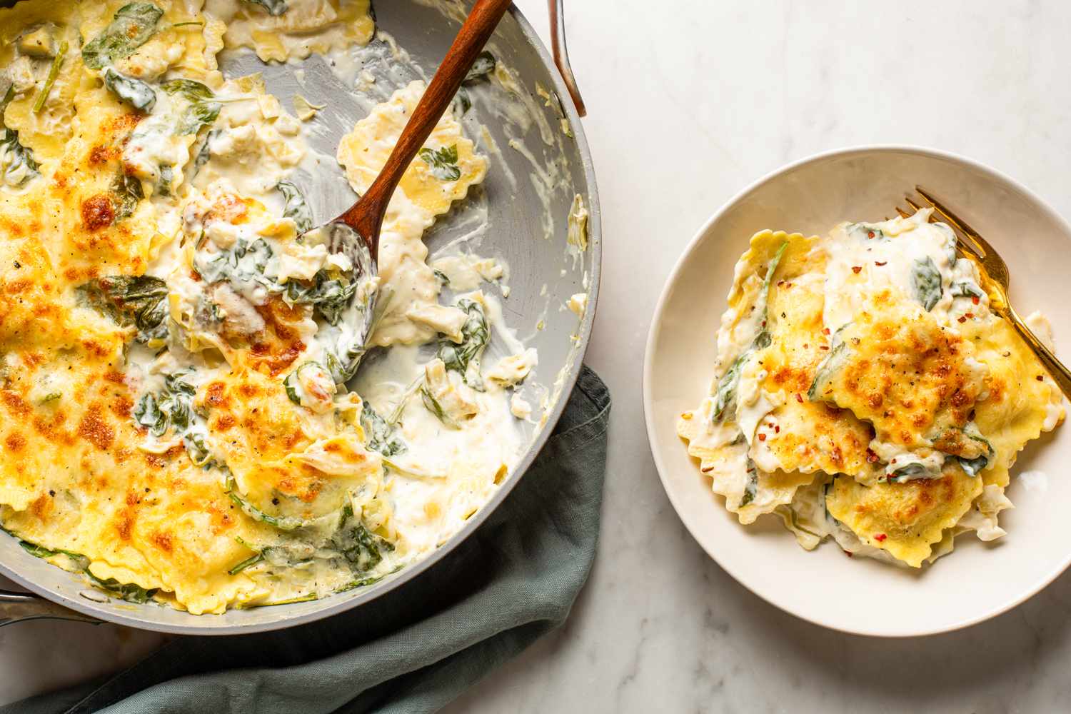 Spinach and artichoke ravioli in a creamy sauce served in a pan and on a plate