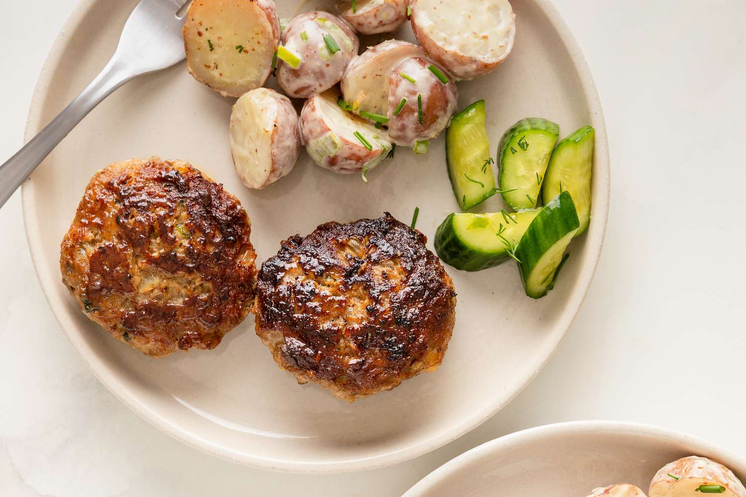 Frikadellen with potato salad and cucumber slices on a plate