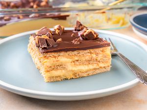 Side view of cake on a blue plate with a fork. Extra plates and the cake pan are visible in the background