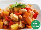 A plate of stir-fried chicken mixed with bell peppers, pineapple chunks, and green garnish