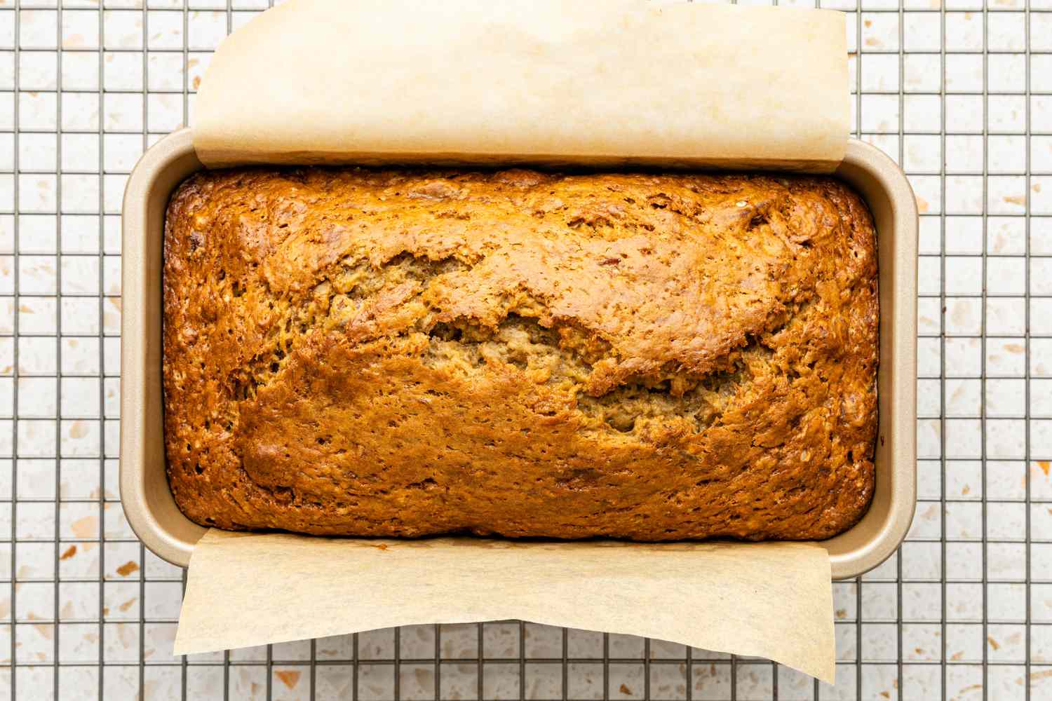 Loaf Pan With Baked Banana Pecan Bread on a Wire Cooling Rack