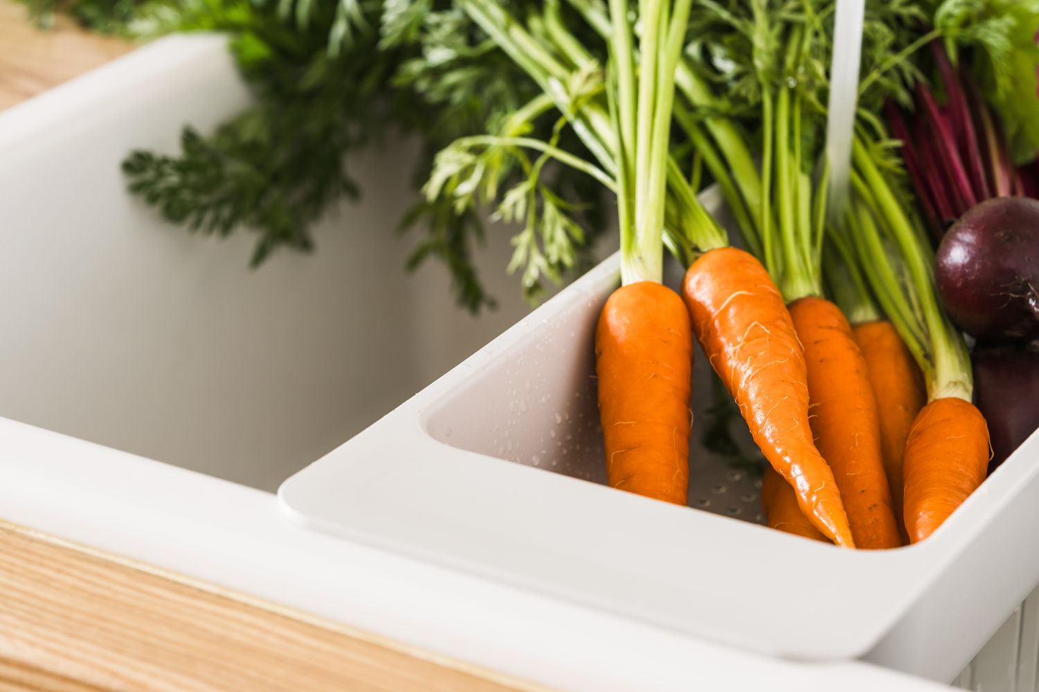 Carrots being washed in a kitchen sink
