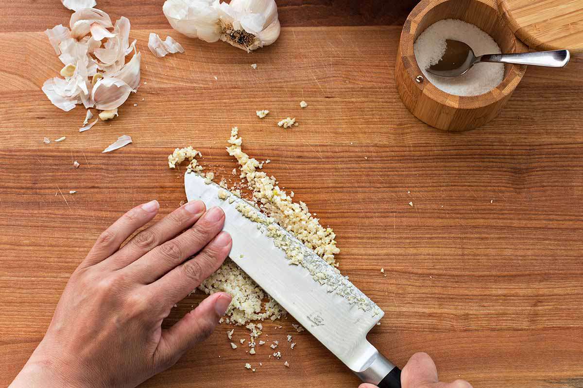 Copycat Guacamole Recipe - person mincing and smashing garlic