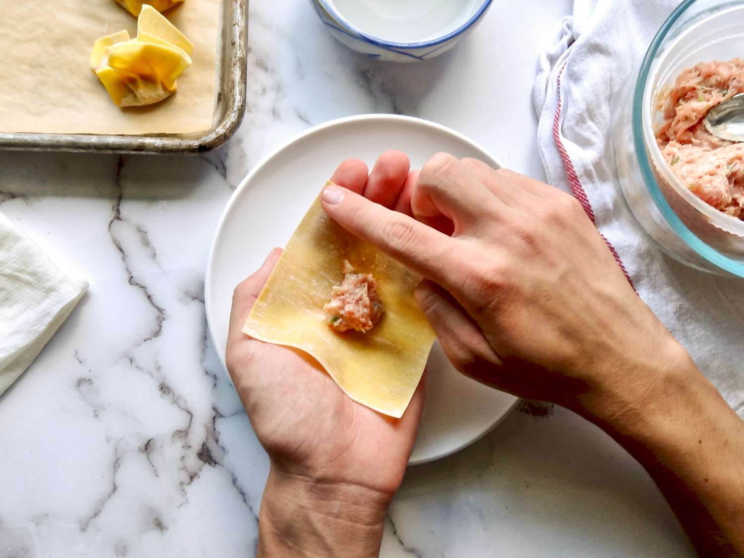 Wetting edge of wonton wrapper to make wonton soup.