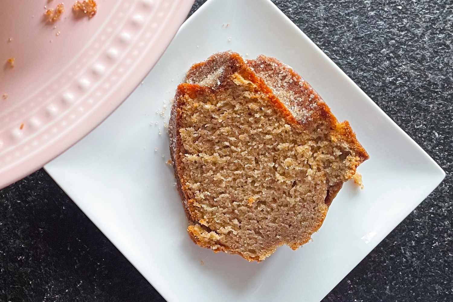 A slice of Martha Stewart's apple cider doughnut cake served on a white square plate