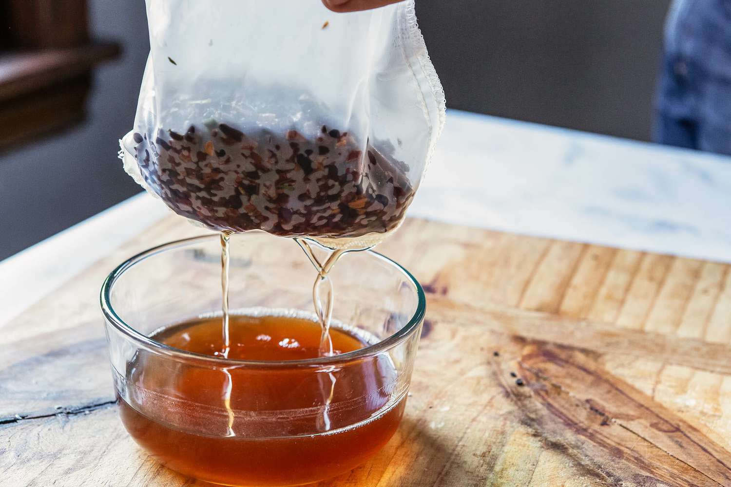 Ingredients for Chocolate bitters in a mesh bag and dripping back into a glass bowl.