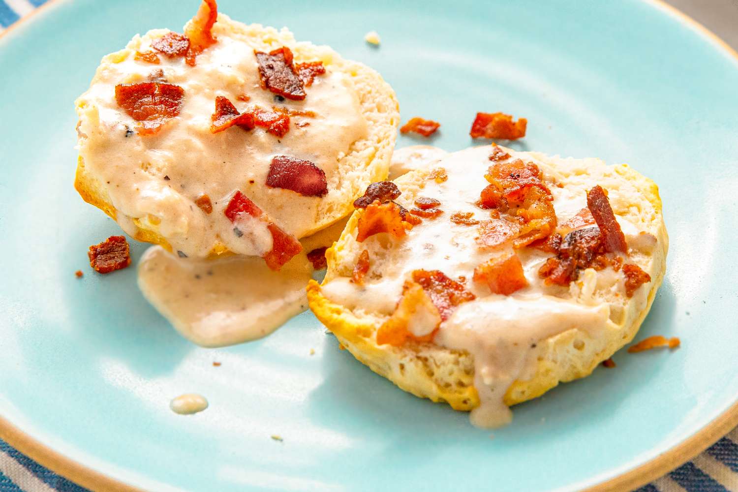 Biscuits topped with gravy and bacon bits on a plate