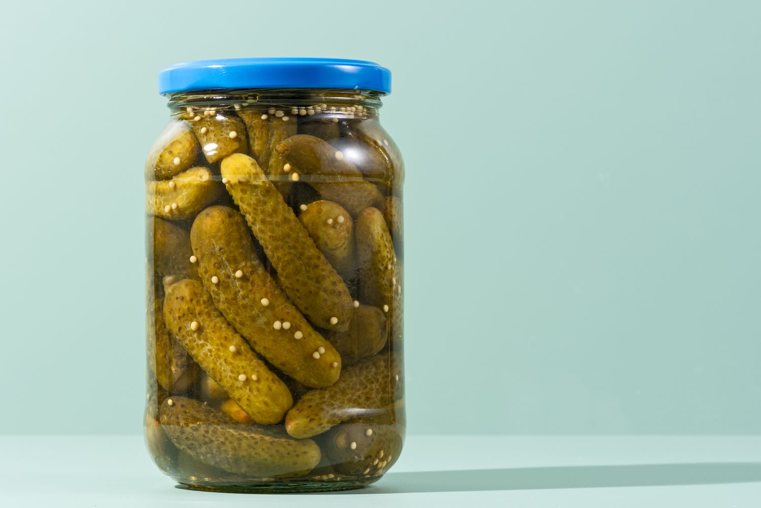 A jar of pickles with a blue lid