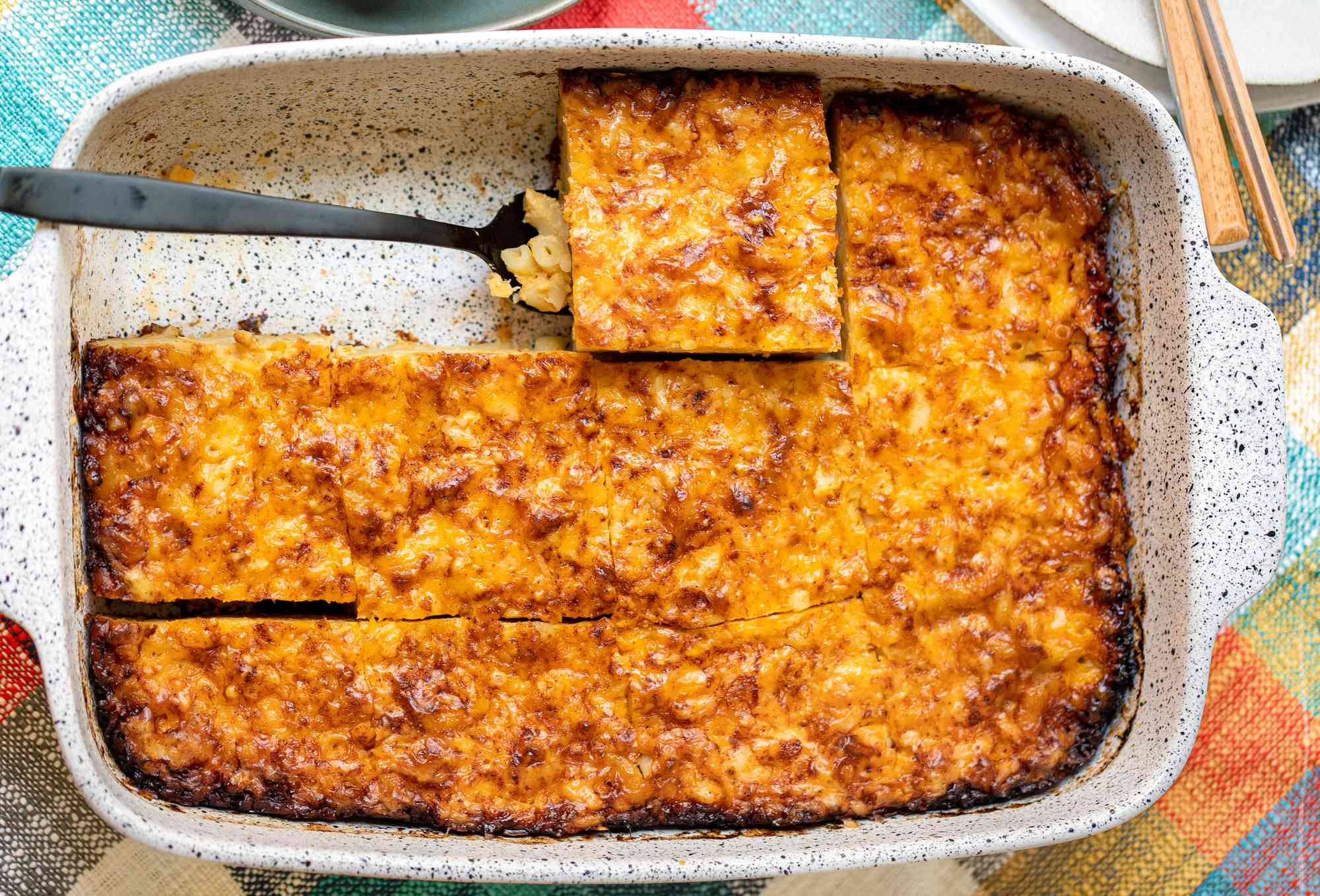 Casserole Dish of Trinidadian Macaroni Pie Cut into Individual Servings with One Piece Lifted Using a Spatula