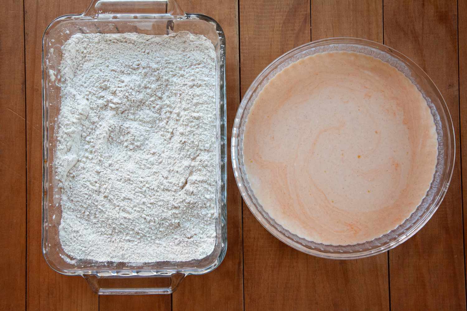 A glass casserole dish with a flour mixture and a round glass bowl with a wet mixture to make Nashville-style hot fried chicken.