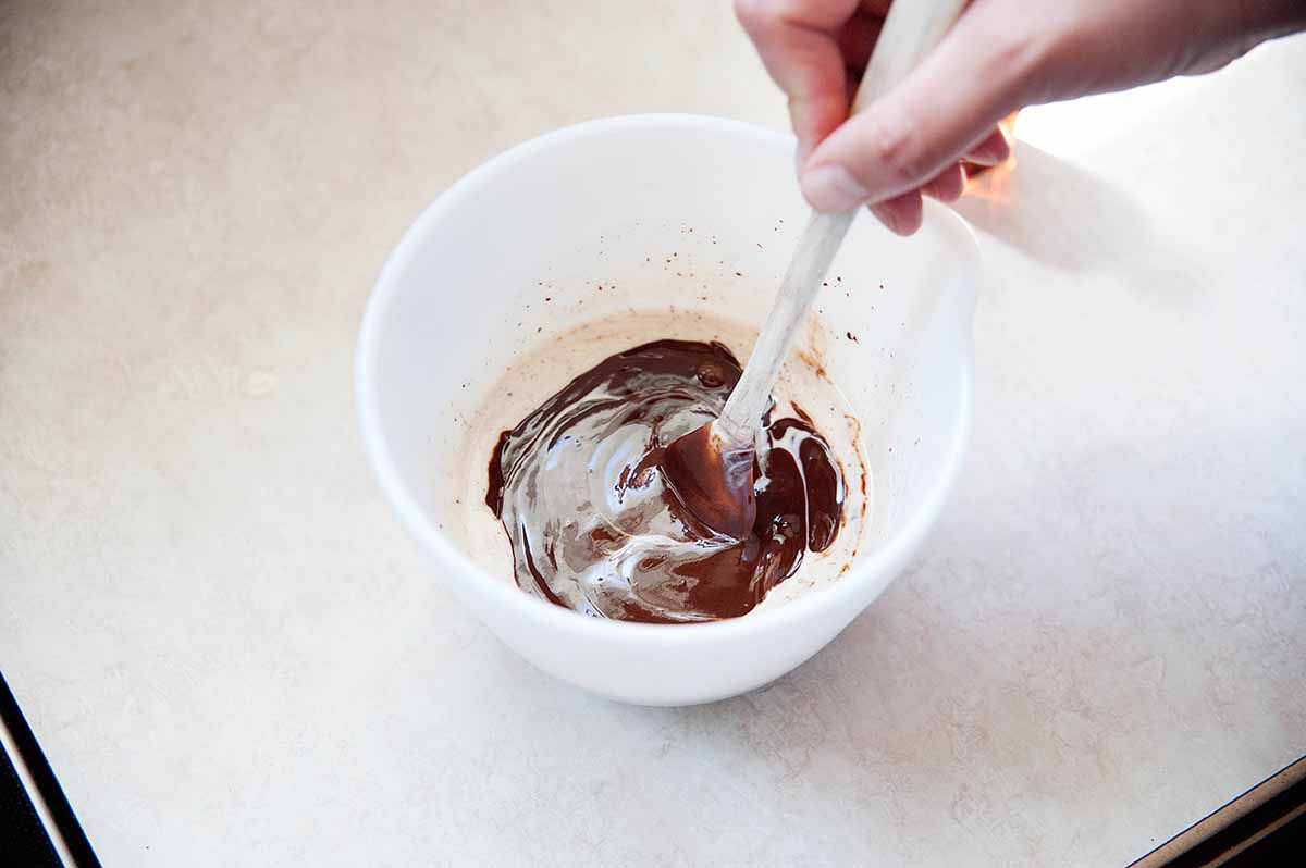 Stirring together melted chocolate and heavy cream.