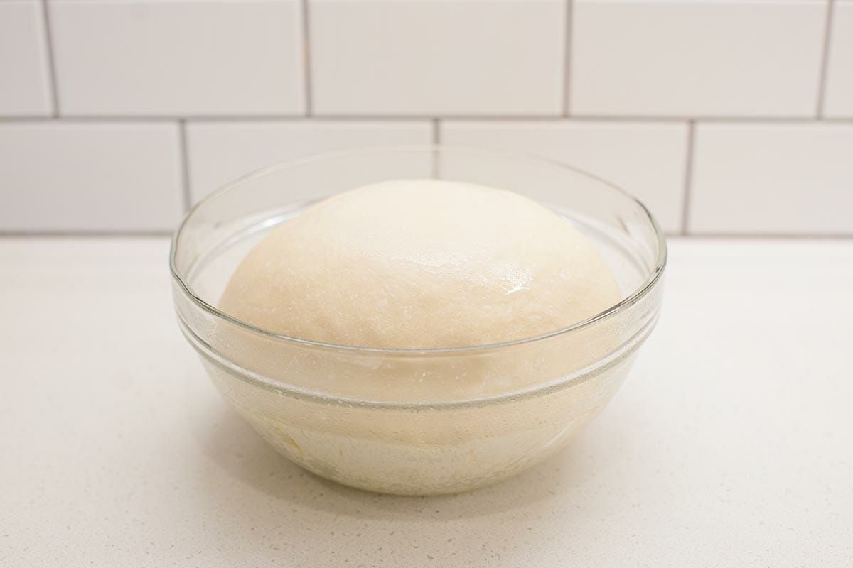 A glass bowl with lion house dinner roll dough rising inside.