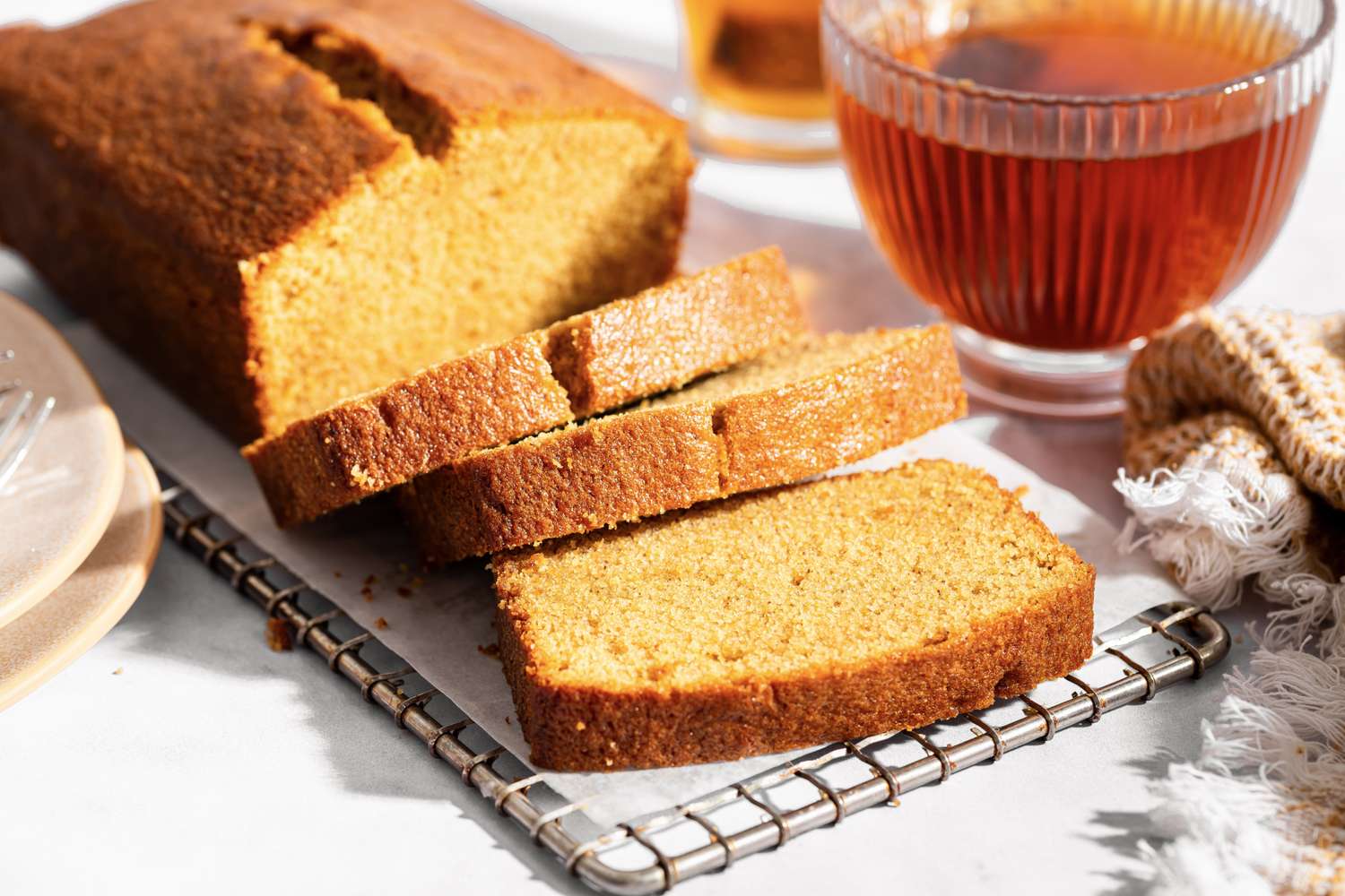 Sliced brown sugar pound cake on a wire rack with a cup of tea in the background