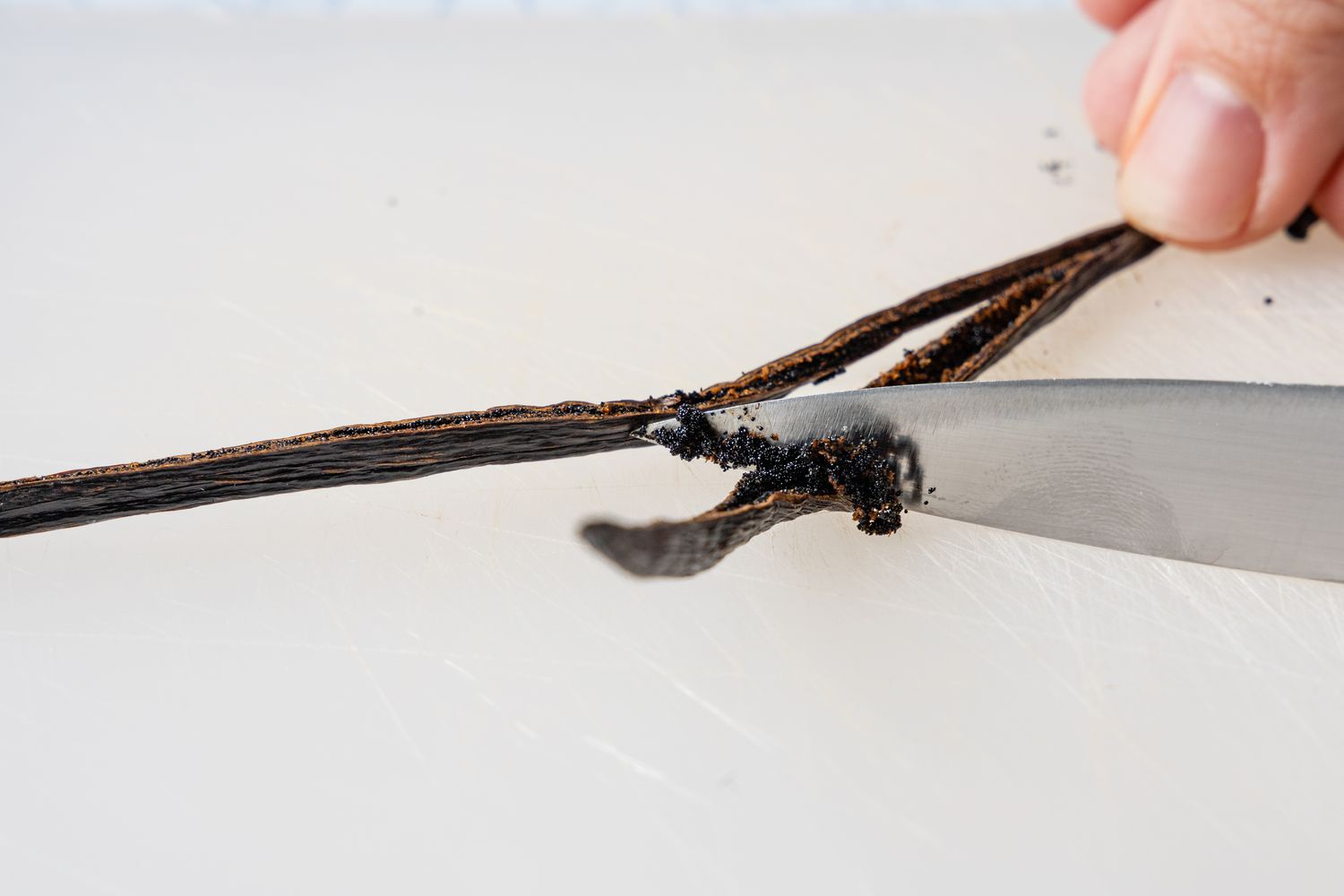 Knife Scraping Vanilla Bean Seeds from a Pod for Vanilla Pudding 